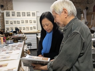 El artista Masafumi Yamamoto enseña un libro a la Cónsul General en su taller, donde se pueden ver grabados