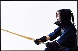 kendoka con la espada de entrenamiento bo, el casco y las protecciones