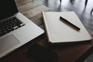 Ordenador, libreta y bolígrafo