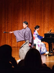 La pianista Yoko Suzuki tocando mientras el actor principal shite Kanji Shimizu baila