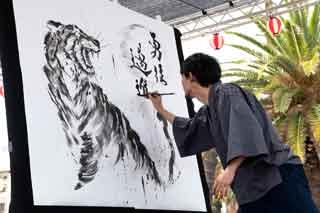 El artista Mitsuru Nagata creando una obra de un león con la técnica de pintura en tinta negra sumie