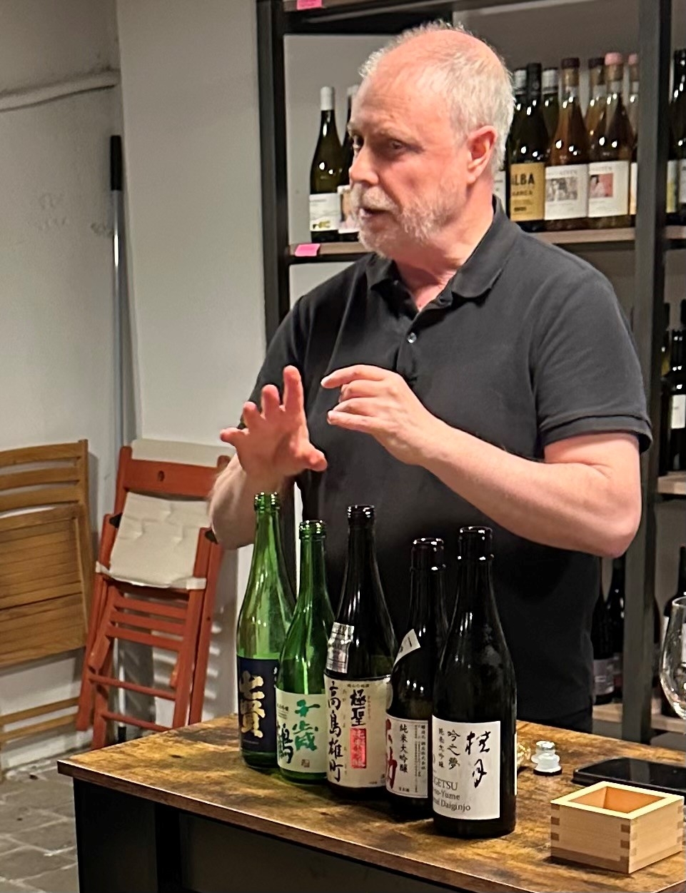 Fotografía de Paco Querol ofreciendo una charla sobre el sake, con cinco botellas de sake delante y un vaso de tipo masu