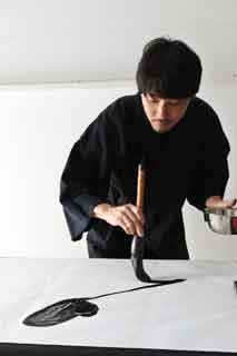 Mitsuru Nagata con un pincel de grandes dimensiones creando una obra sobre papel washi sobre una mesa